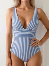 Woman wearing a blue and white striped one-piece swimsuit with a deep V-neckline and cinched waist detail.