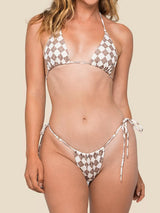 Woman wearing a brown and white checkerboard print halter bikini top and matching string bikini bottom.