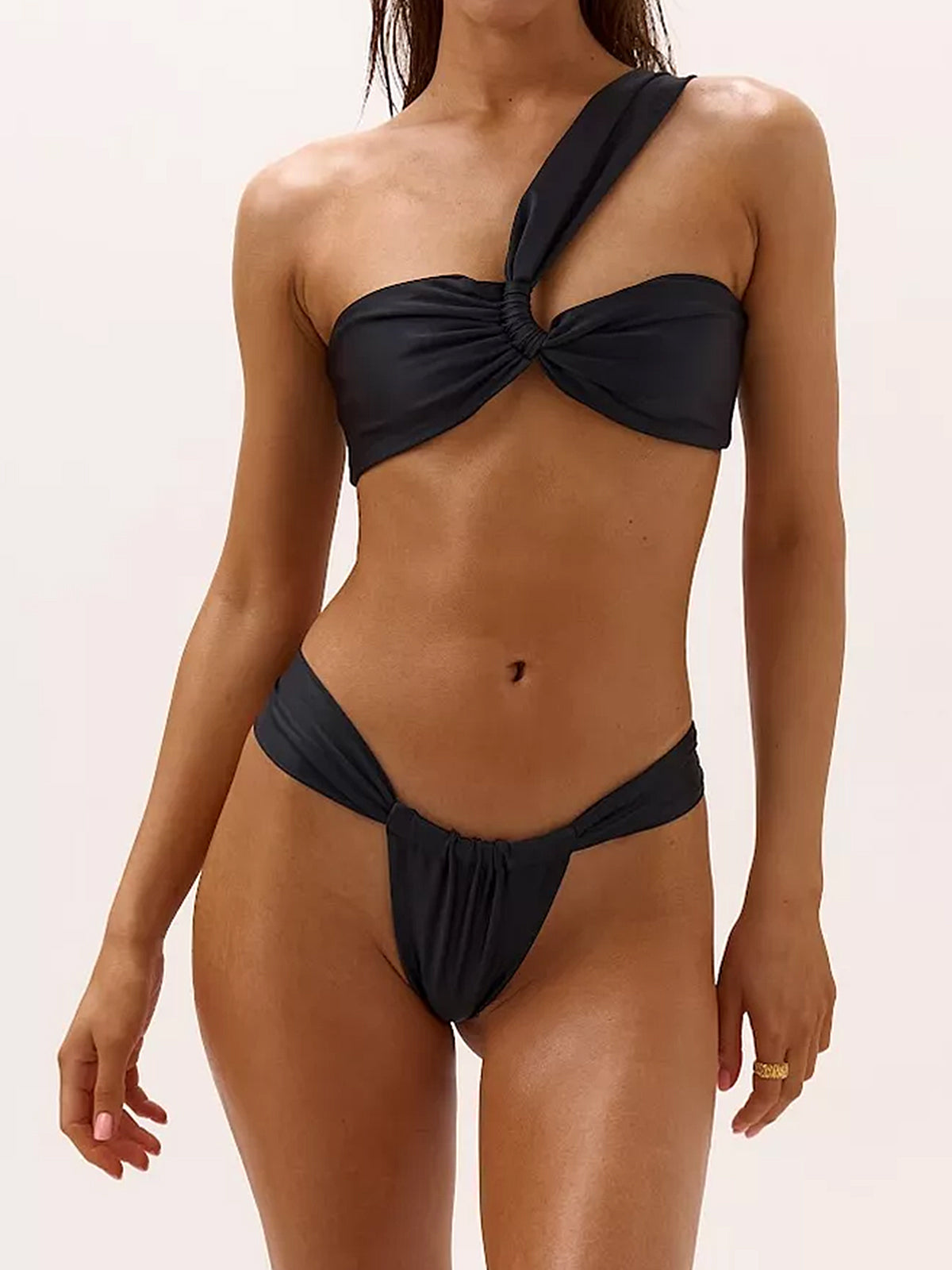 Woman wearing a black one-shoulder bikini with a knotted bust and high-cut bottoms.