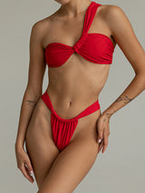 Woman wearing a red one-shoulder bikini with a knotted bust and high-cut bottoms.