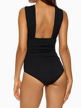 Black one-piece swimsuit with cross-over halter neckline and ruched waist, hands clasped in front, front view
