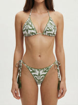 Front view of a woman wearing a white and green patterned bikini with tassels.