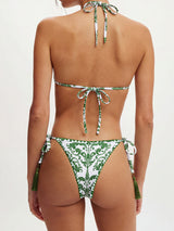 Back view of a woman wearing a white and green patterned bikini with tassels.