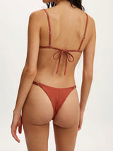 back view of a woman wearing a rust-colored bikini with adjustable tie closures