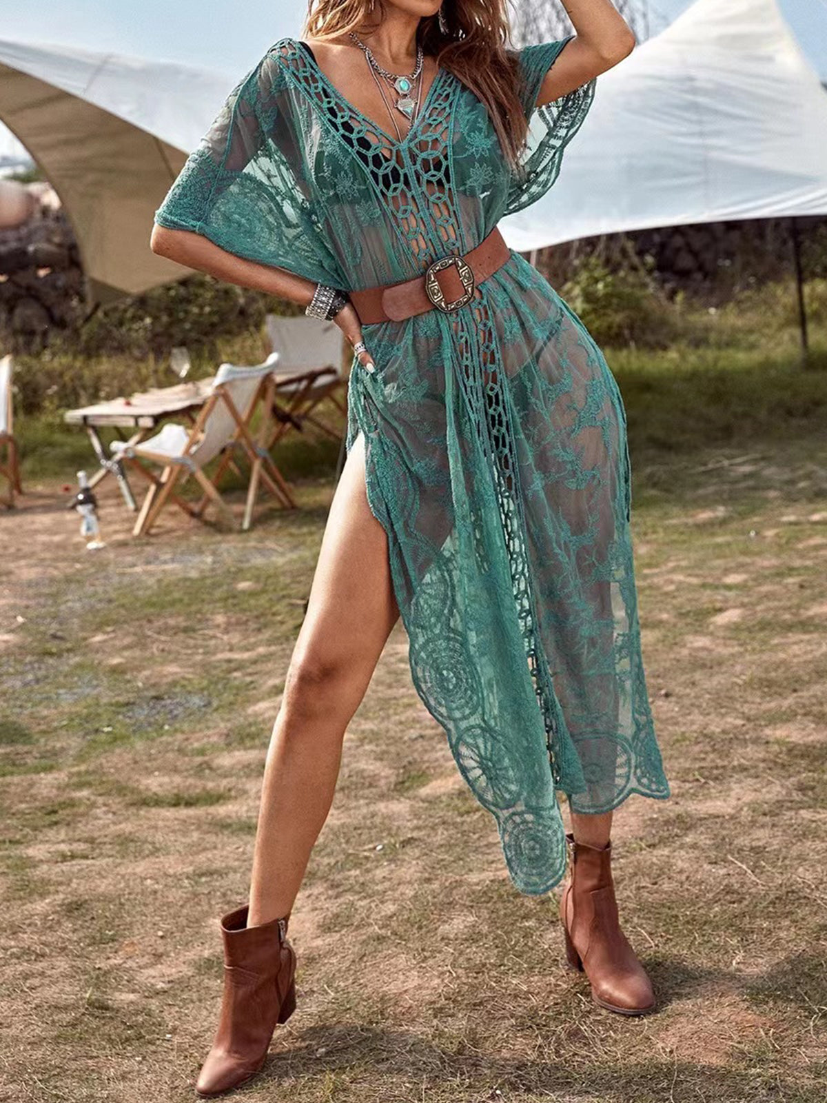 woman wearing a teal sheer lace maxi cover-up with high side slits, belted at the waist
