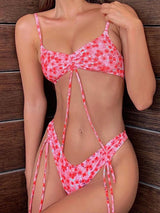 Woman wearing a pink floral print bikini with adjustable tie straps and cinched bust.