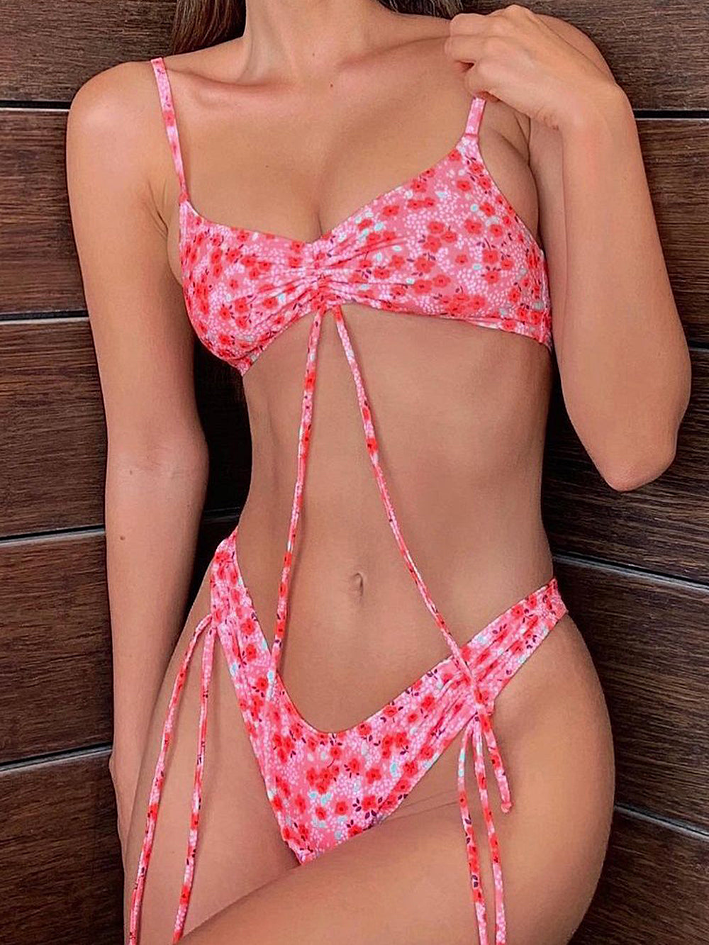 Woman wearing a pink floral print bikini with adjustable tie straps and cinched bust.