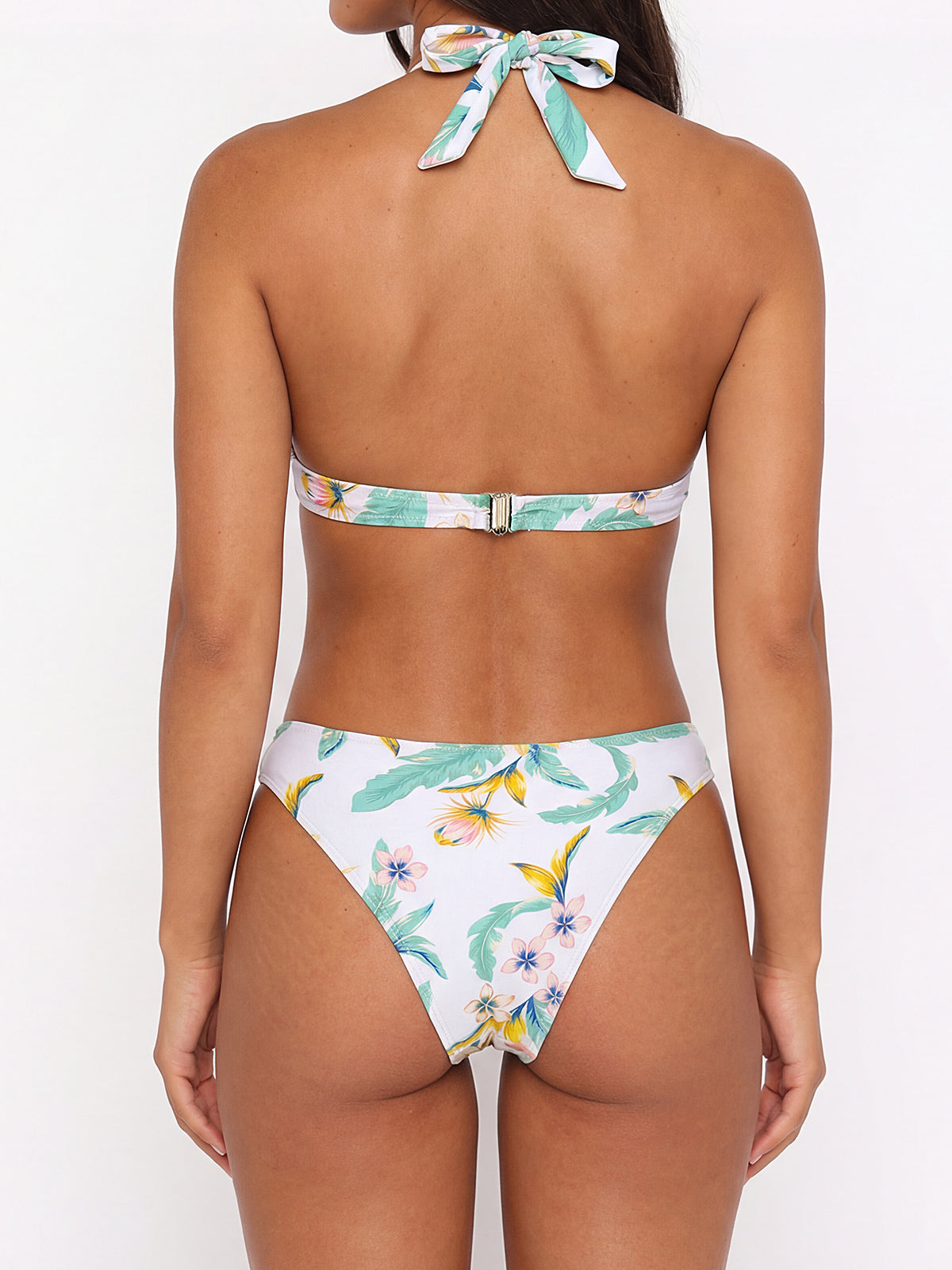 Back view of a woman wearing a white bikini with a floral print, showcasing the halter top and bikini bottoms.