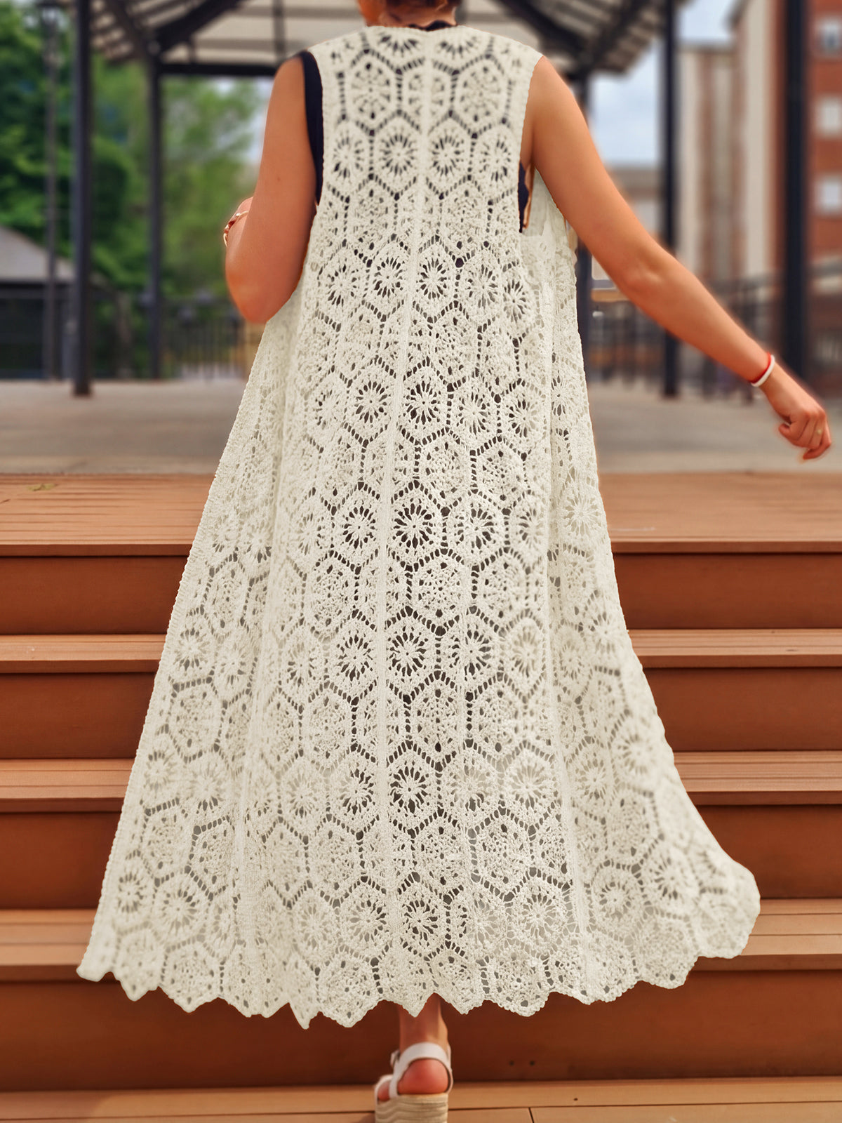 Back view of a woman wearing a long, flowing white crocheted lace vest