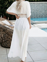 Back view of a woman wearing a white sheer maxi cover-up with a V-neck and lace waist detail.