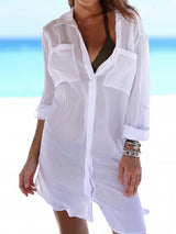 Woman wearing a white sheer button-down tunic over a bikini top at the beach