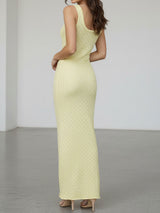 Back view of a woman wearing a pale yellow sleeveless maxi knit dress with a scoop neck.