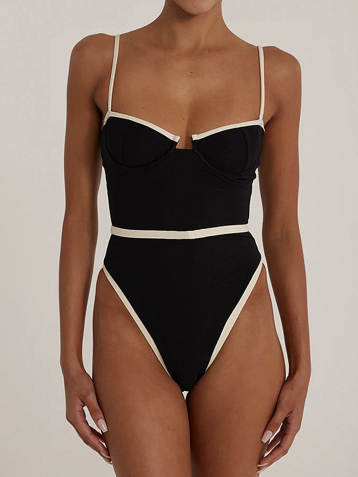 Front view of a black one-piece swimsuit with cream trim, featuring a plunging V-neck and high-cut legs.