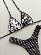 Close-up of a bikini top with a cow print and brown trim, laid flat.
