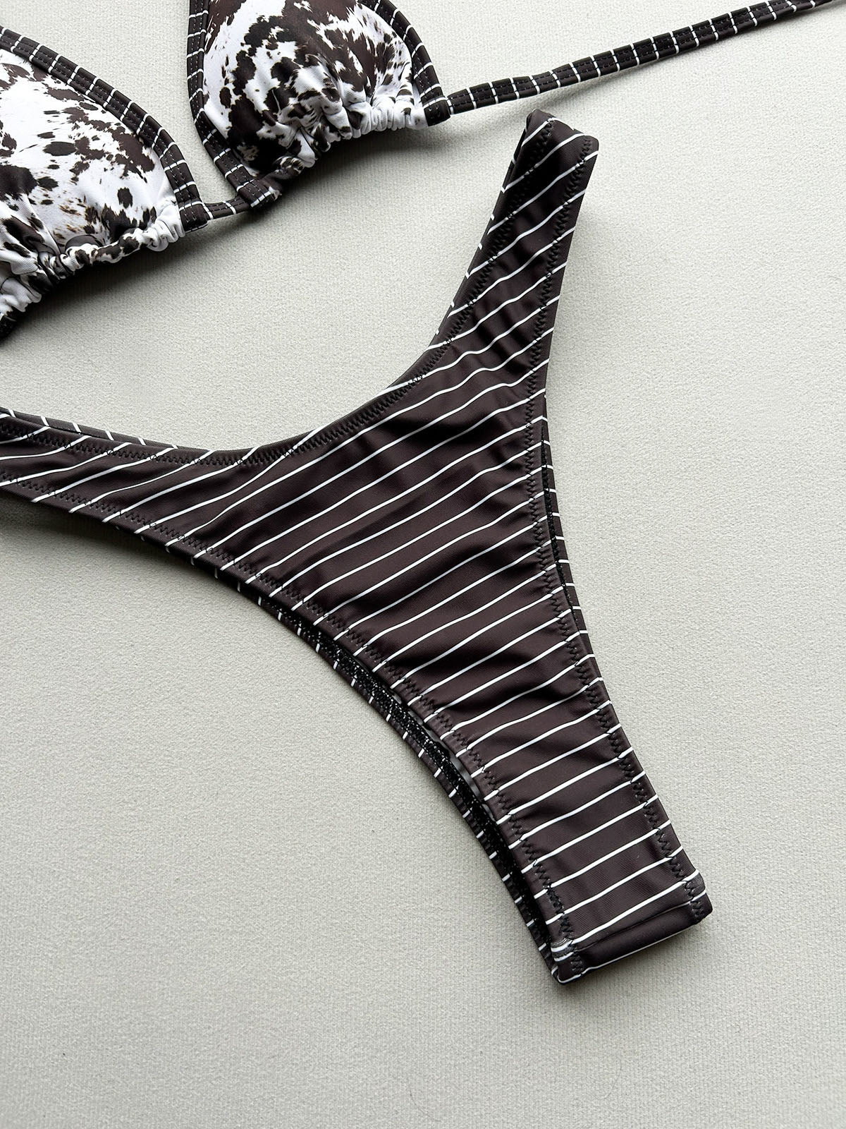Close-up of a bikini bottom with white stripes on a brown background, laid flat.