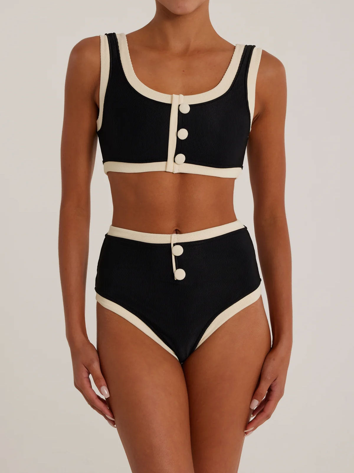 Woman wearing a black and cream ribbed bikini set, front view