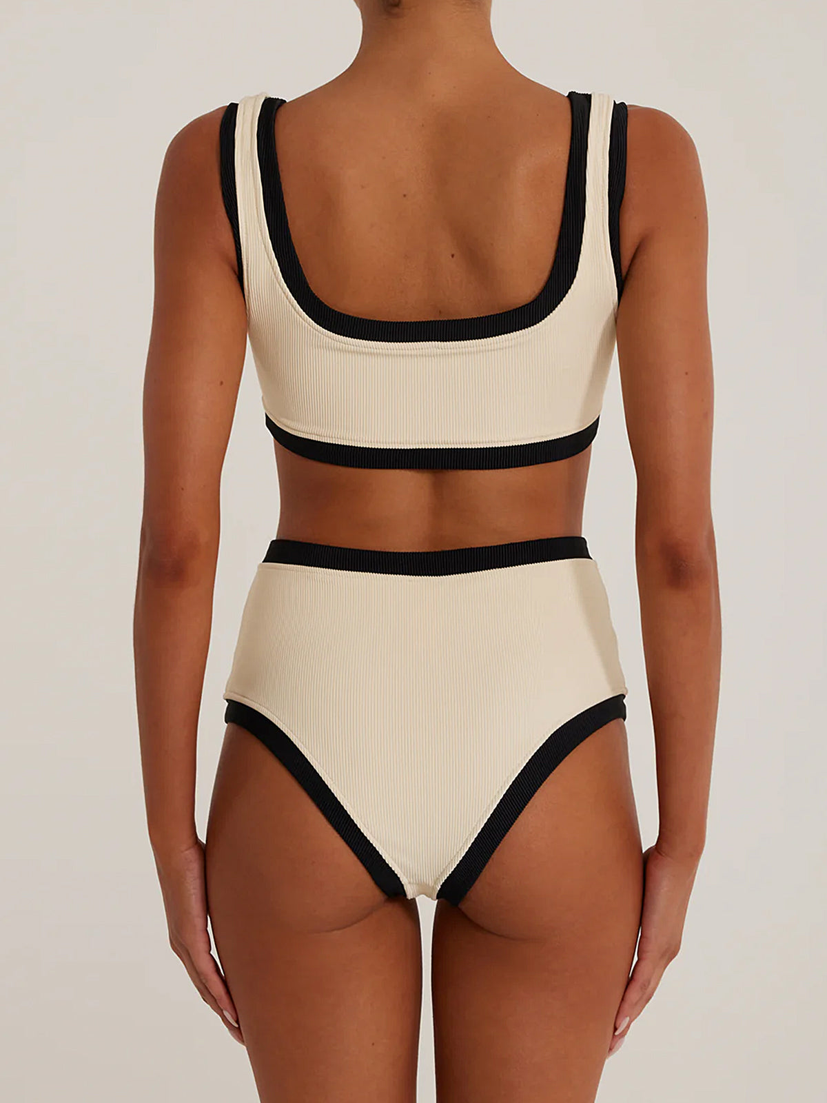 Woman wearing a cream and black ribbed bikini set, back view