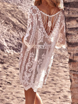 Woman in a white lace beach cover-up leaning against a palm tree.