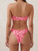 Front view of a woman in a strapless bandeau bikini top with a floral pattern and a decorative gold accent.