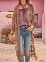 Woman wearing a brown lace kimono over a mauve tank top and blue jeans.