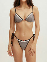 Woman wearing a black and white gingham bikini with ruffled trim and cherry embellishment.