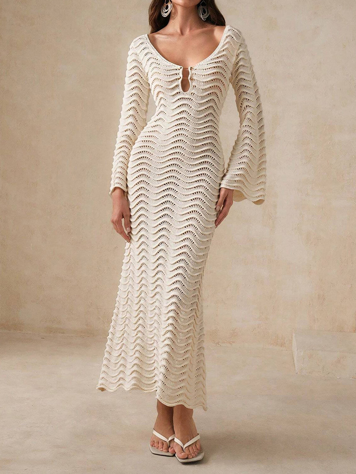 Woman wearing a cream knit maxi dress with bell sleeves and a keyhole neckline.