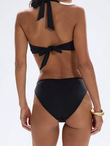Back view of a woman wearing a black halter neck bikini top with a tie closure.