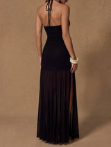 Back view of a woman in a black halter maxi dress with a sheer overlay skirt