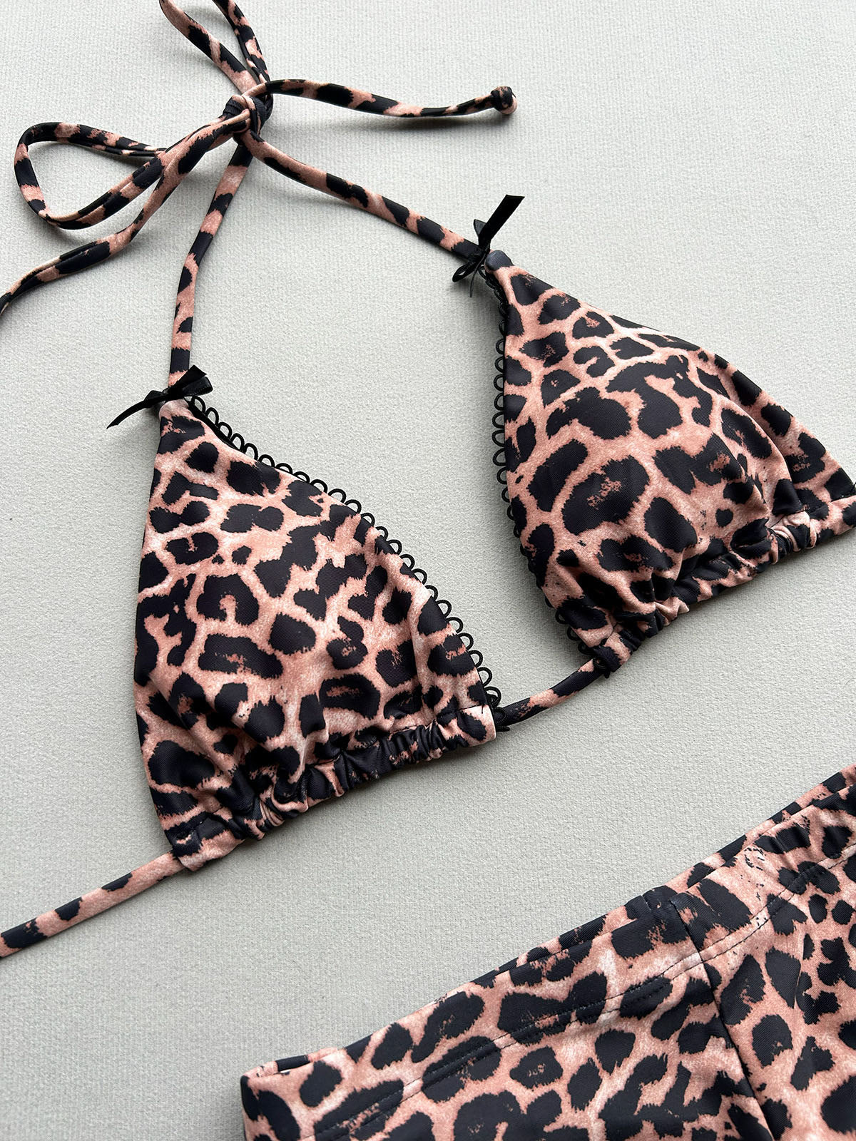 Close-up of the leopard print triangle bikini top with lace trim and bow accents.