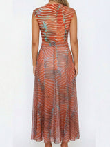 back view of a woman wearing a long orange and blue striped sheer knit dress