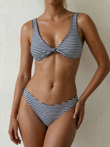 Woman wearing a blue and white striped bikini with a twisted front top and high-cut bottoms