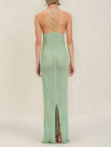 back view of woman wearing a long, light green, chevron-patterned knit halter dress with an open back detail