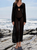 Woman wearing a black crochet maxi dress and bikini on a rocky coastline.