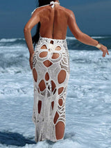 Woman wearing a white crocheted maxi dress from the back on a beach