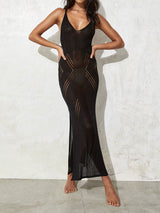 woman wearing a black sheer knit maxi dress with geometric cutouts and a high slit, hands on hips