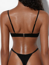 Back view of a woman wearing a black sheer mesh and smooth fabric lingerie set with adjustable straps
