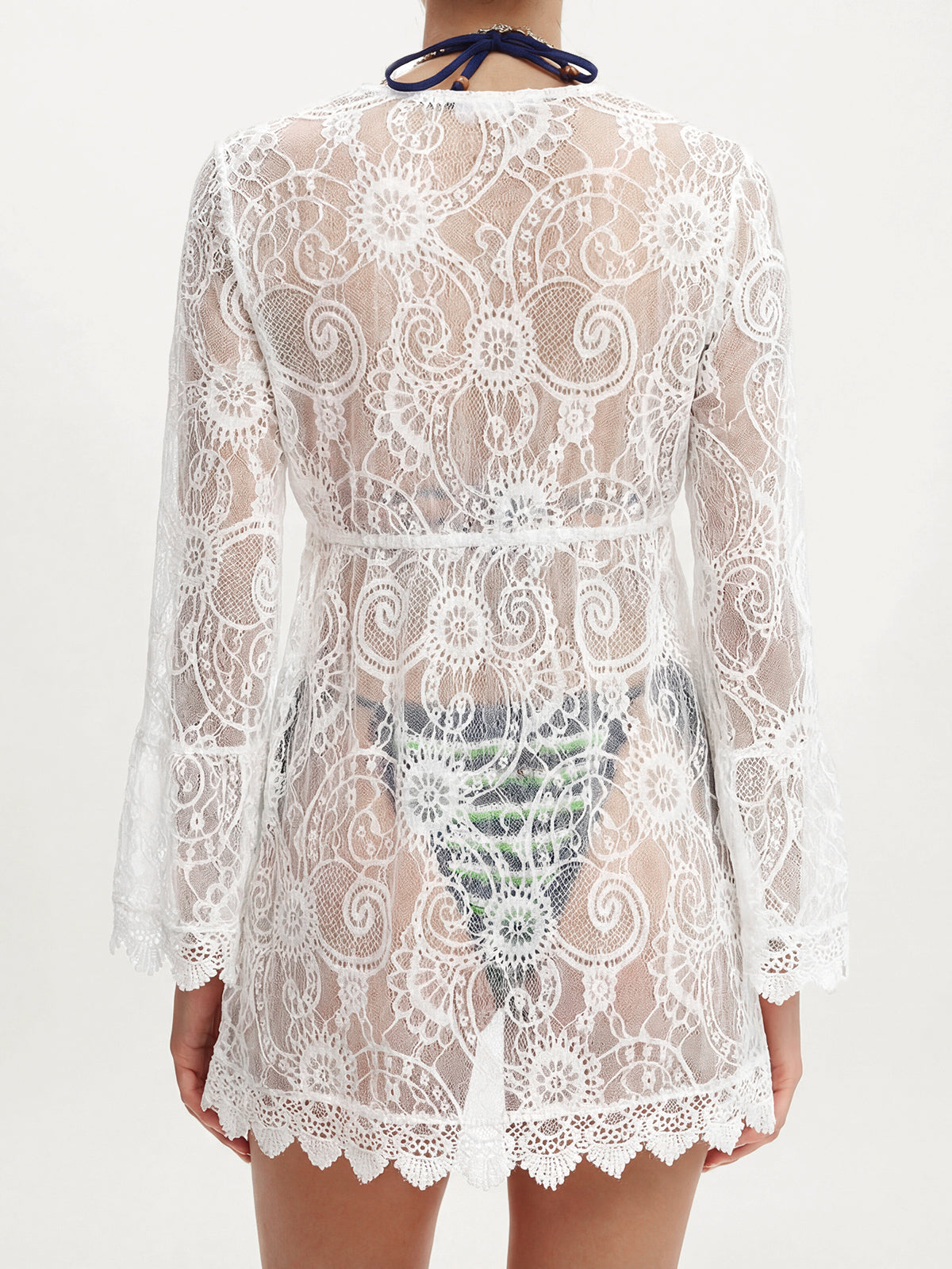 Back view of a woman wearing a white lace tunic, showing the intricate lace pattern.