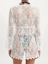 Back view of a woman wearing a white lace tunic, showing the intricate lace pattern.