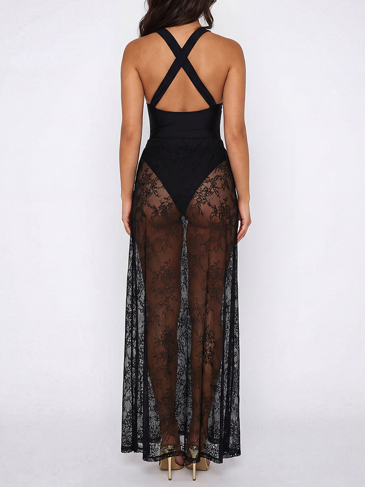 Back view of a woman in a black maxi dress with a sheer lace overlay and crisscross straps.