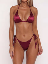 Woman wearing a burgundy satin triangle bikini set with adjustable string ties