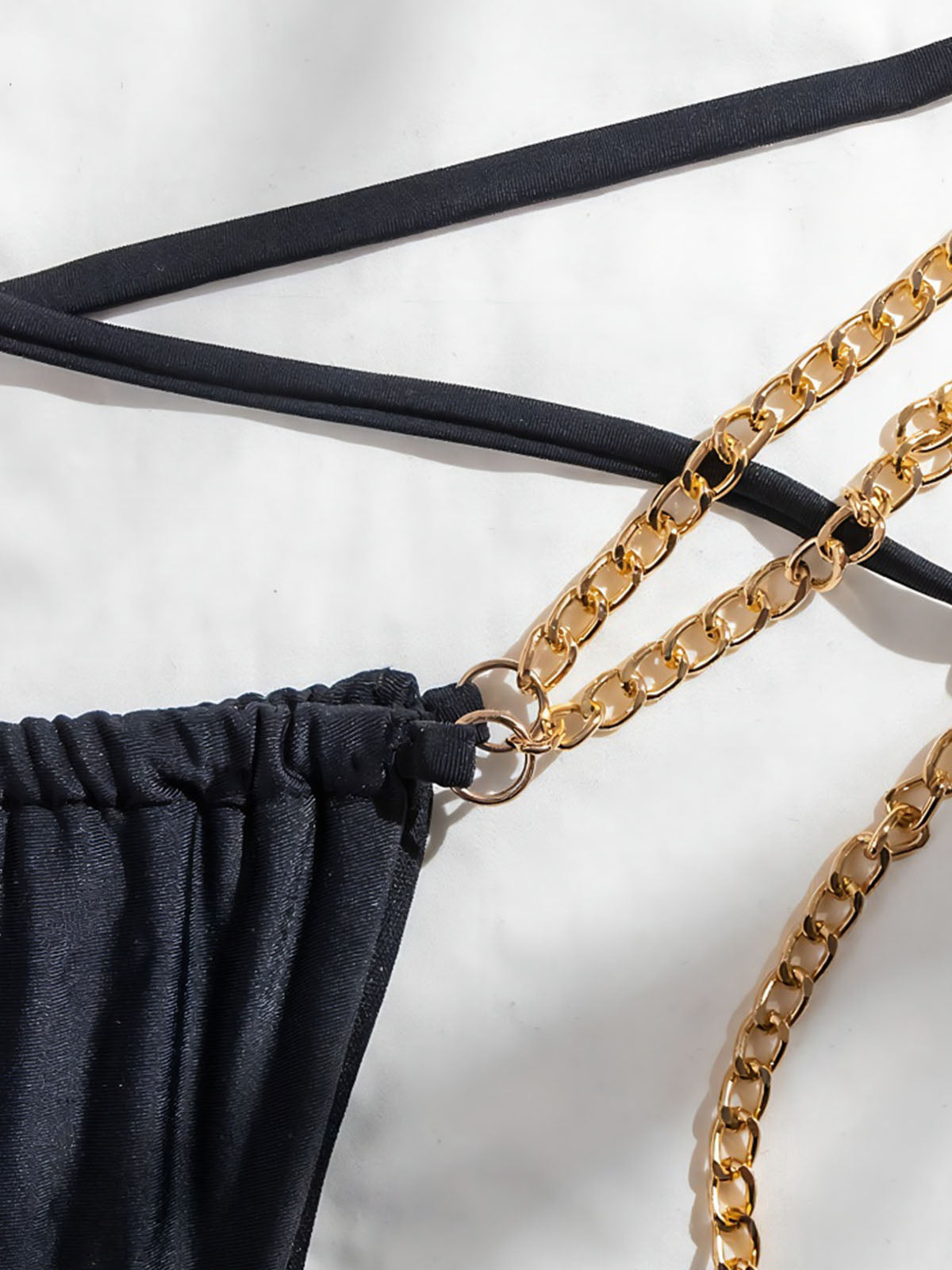 Close-up of the black bikini bottom showing chain attachment detail.