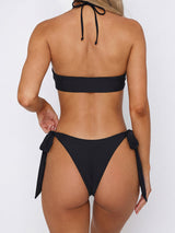 Front view of a black two-piece bikini with a halter neckline and gold ring accents