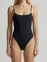 Woman wearing a black one-piece swimsuit with all-over embellishments.