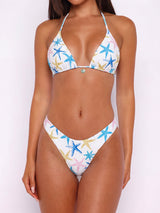Front view of a white bikini with a starfish print, featuring a halter top and low-rise bottoms.